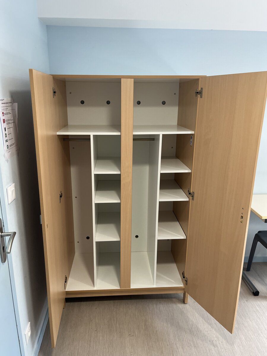 Armoire ouverte dans une chambre de l'internat avec étagères de rangement