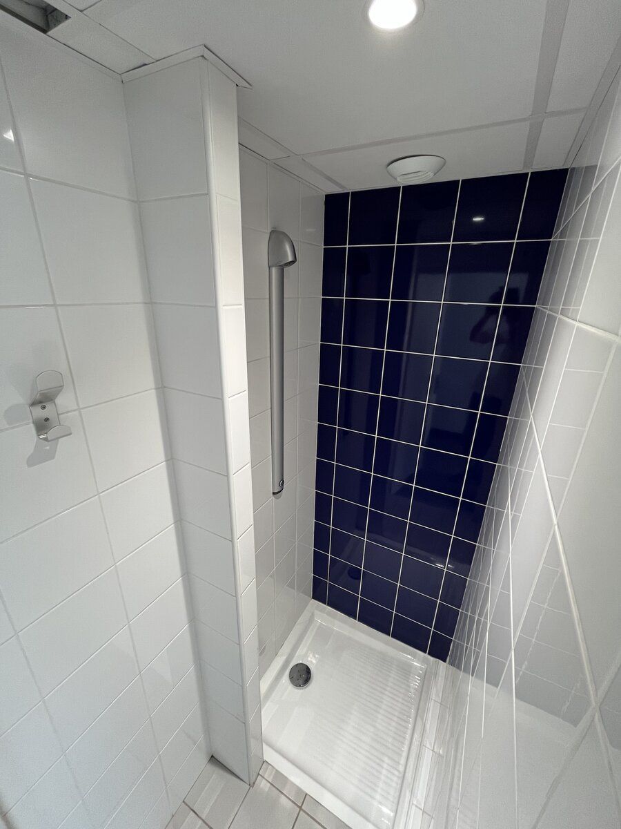 Douche individuelle de l'internat avec carrelage bleu et blanc