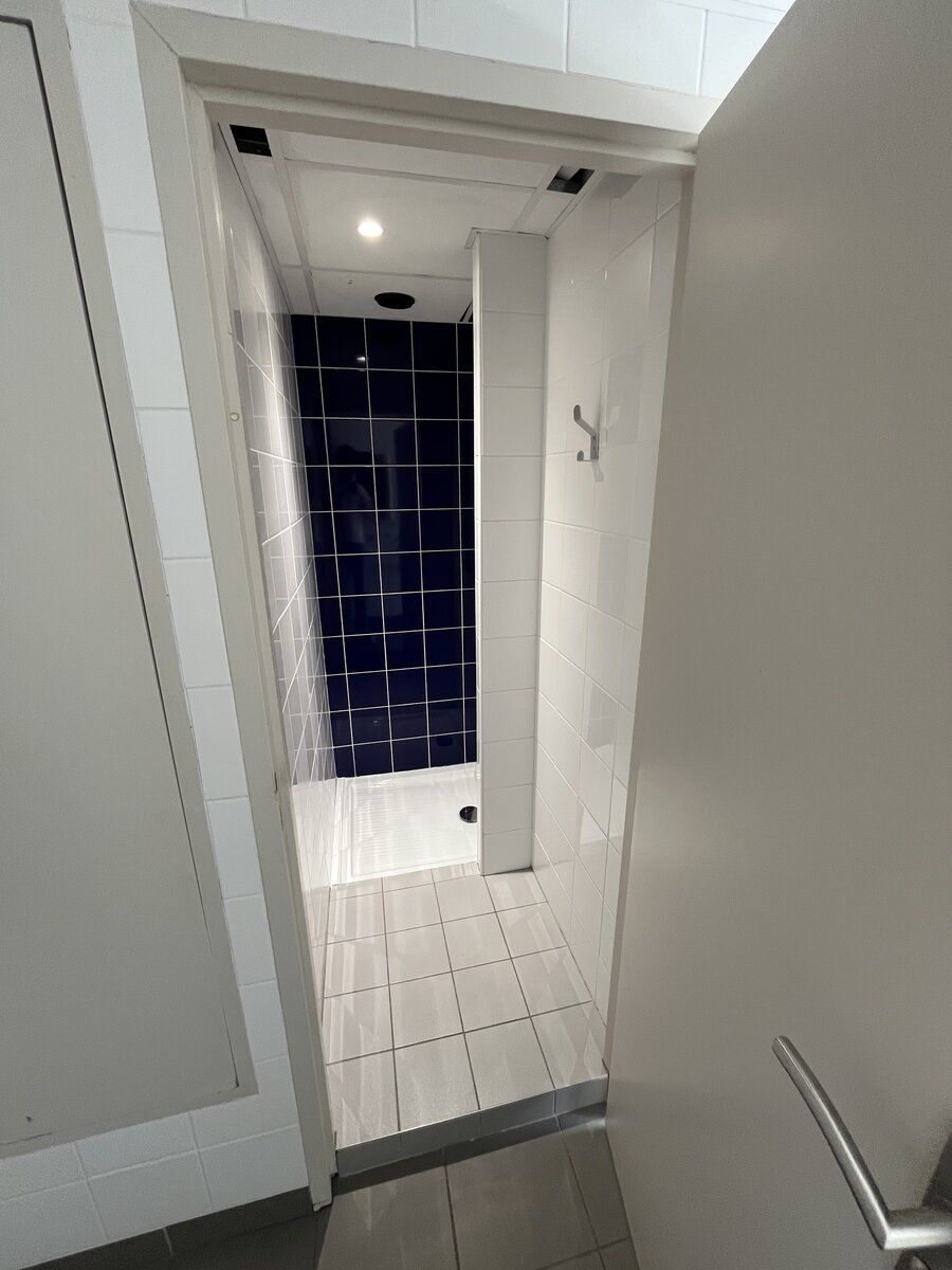 Cabine de douche carrelée bleu marine de l'internat