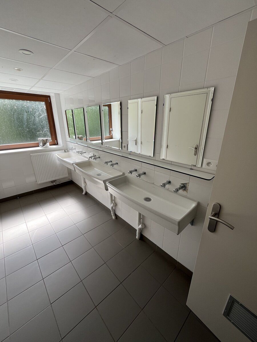 Sanitaires de l'internat avec alignement de lavabos et miroirs