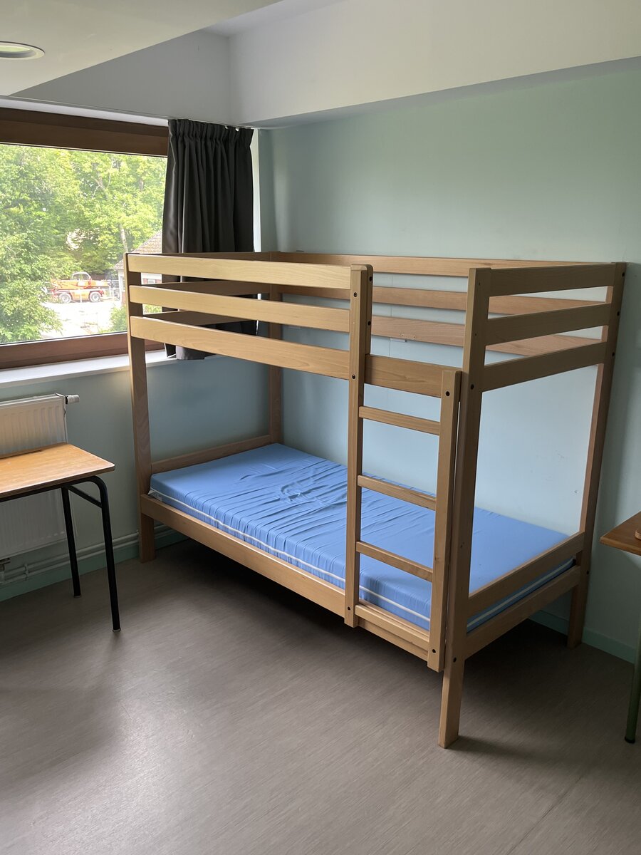Chambre d'internat avec lit superposé en bois et vue extérieure
